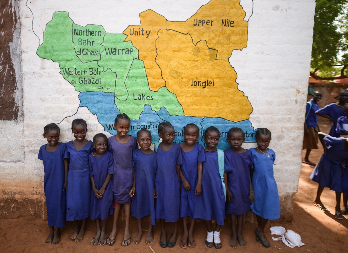 Children standing next to the southsudan map